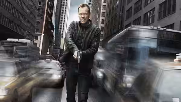 Jack Bauer (Kiefer Sutherland) standing in a busy city street holding a gun