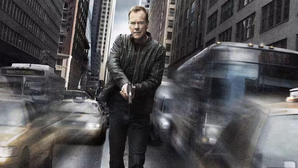 Jack Bauer (Kiefer Sutherland) standing in a busy city street holding a gun