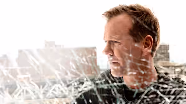 Jack Bauer (Kiefer Sutherland) peering through shattered glass overlooking a city