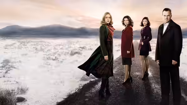 Three women and a man standing on a snowy rural road
