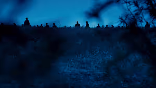 A group of armed figures standing on a ridge at twilight