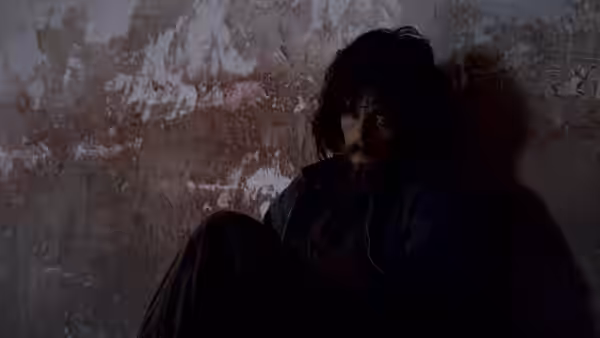 Che Guevara (Benicio del Toro) resting against a wall in a dimly lit room