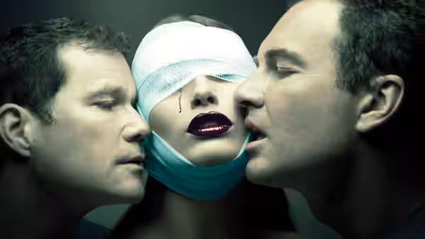 Two men lean close to a bandaged woman with dark lipstick