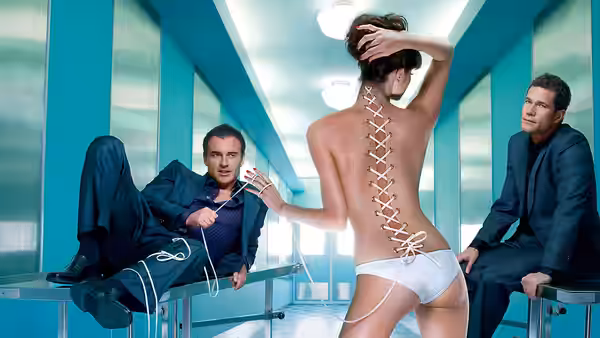 Two men in suits flank a woman with corset lacing on her back