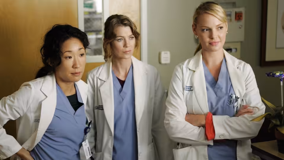 Cristina Yang (Sandra Oh), Meredith Grey (Ellen Pompeo) and Izzie Stevens (Katherine Heigl) standing in a hospital corridor