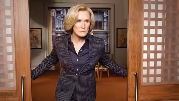 Patty Hewes (Glenn Close) holding open double doors in an office