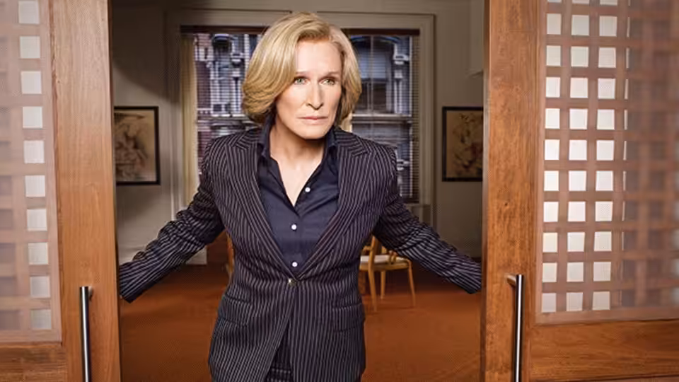 Patty Hewes (Glenn Close) holding open double doors in an office