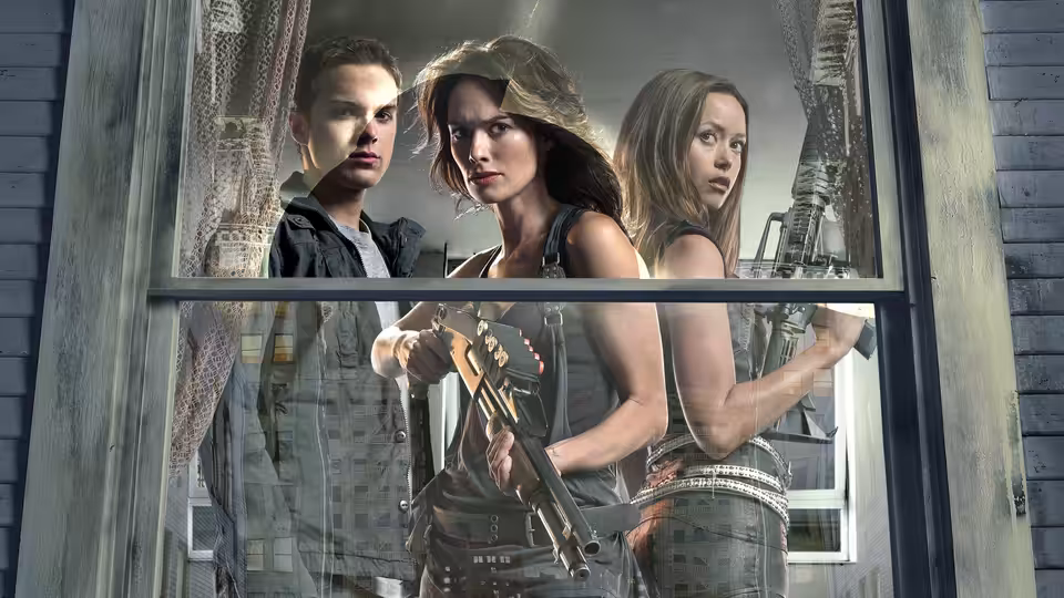 Sarah Connor holding a rifle by a broken window with two companions