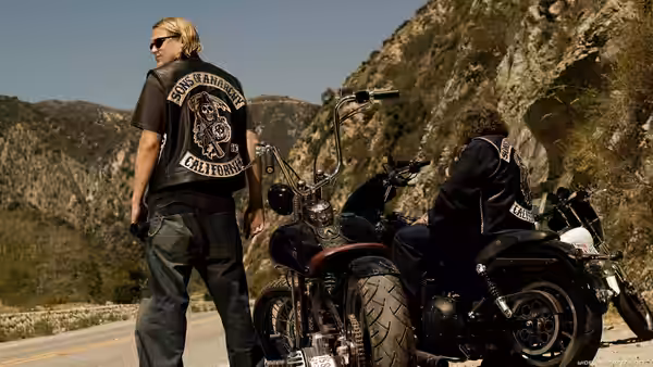 Jax Teller (Charlie Hunnam) standing beside his motorcycle on a mountain road