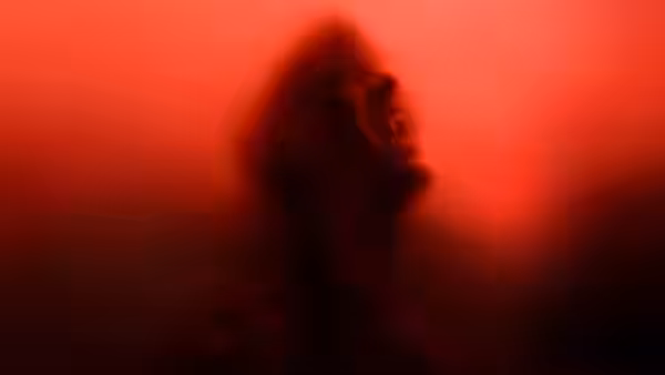 Blurred figure of a person with open mouth in red light