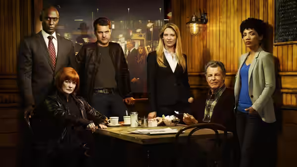 Six adults gathered around wooden table with coffee cups in wood-panelled bar