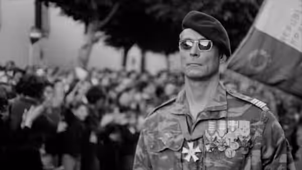 Colonel Philippe Mathieu (Jean Martin) in camouflage uniform marching before a cheering crowd
