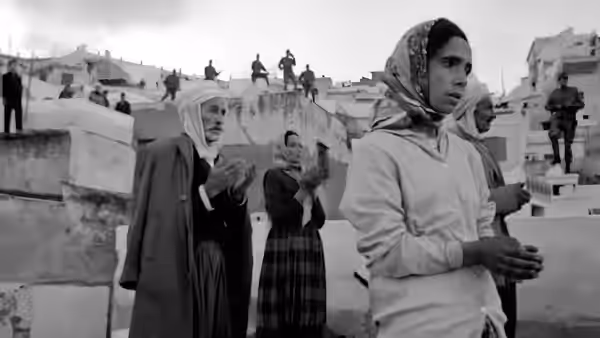 Women praying on a rooftop as soldiers stand guard on surrounding buildings