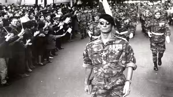 Colonel Philippe Mathieu (Jean Martin) leading troops past civilians saluting along the street