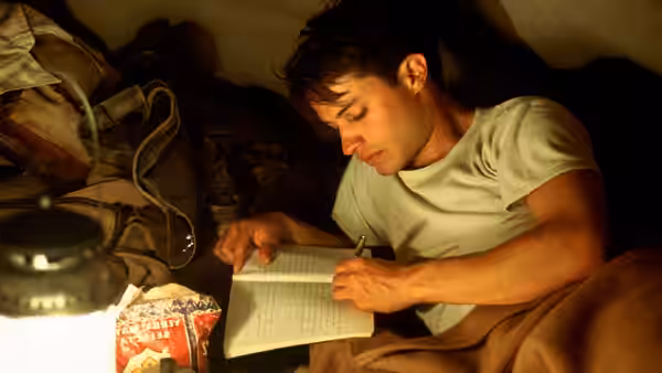 Ernesto (Gael García Bernal) writing in a notebook inside a tent at night