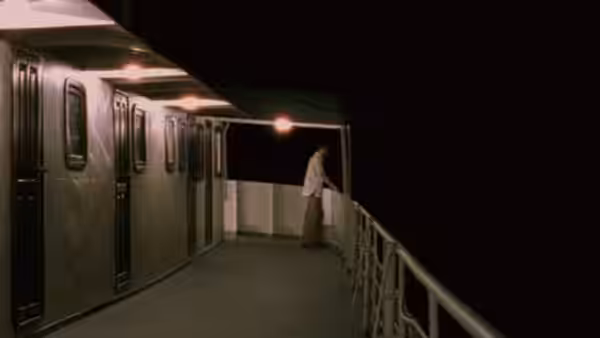 A young man in a white shirt standing alone on a ship's deck at night