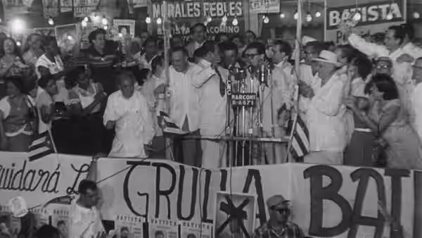A crowd gathers behind banners and signs at a public rally