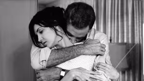 A man embraces a woman from behind as she leans against him