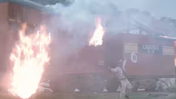 A soldier aiming a pistol next to a burning railway carriage