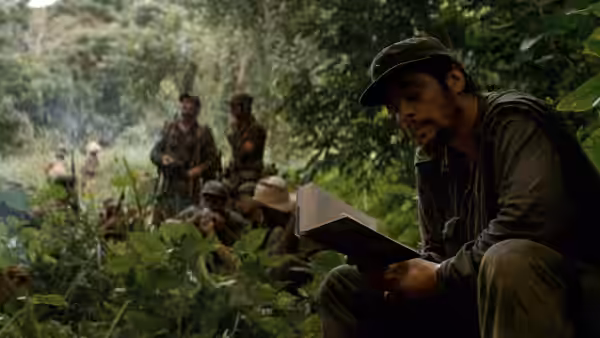 Ernesto Che Guevara (Benicio del Toro) reading a book while seated in the jungle