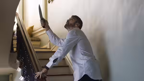 Harry Pfarrer (George Clooney) climbs a staircase holding a knife