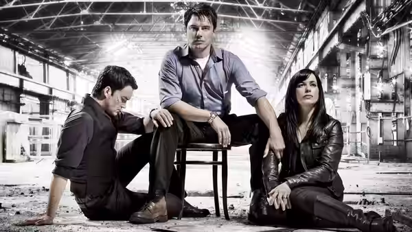 Jack Harkness (John Barrowman) sits on a stool in an empty warehouse