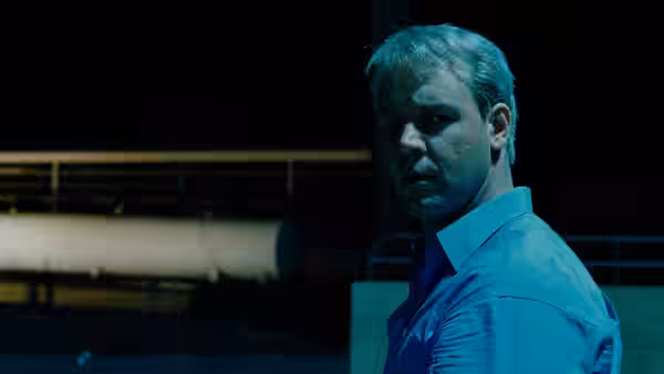 Jeffrey Wigand (Russell Crowe) standing outdoors near industrial pipes at night