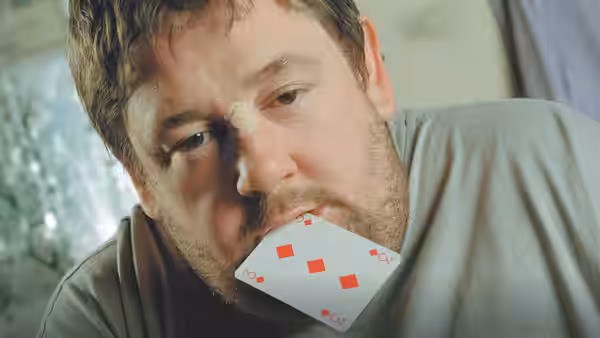 Moz (Johnny Vegas) holding a playing card between his teeth