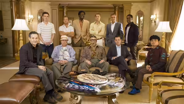 The Ocean's crew gathered together in a luxurious hotel suite around a table