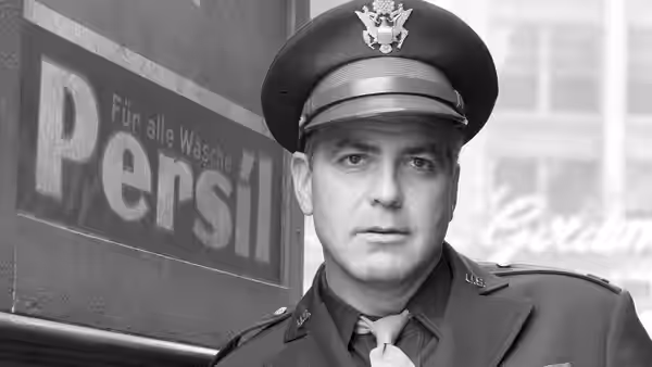 U.S. officer in uniform standing before a German sign on a wall