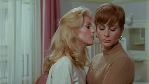 Séverine (Catherine Deneuve) leans close to Renée (Macha Méril) indoors