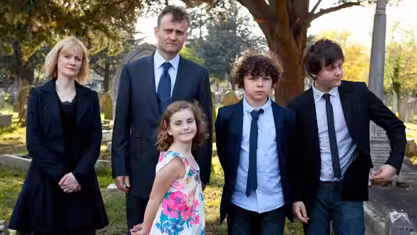 Sue (Claire Skinner) and Pete (Hugh Dennis) stand with children in a cemetery