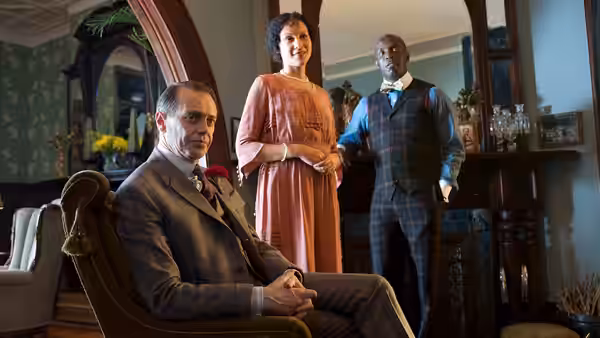 Nucky Thompson (Steve Buscemi) seated while Margaret Schroeder (Kelly Macdonald) and Chalky White (Michael K. Williams) stand nearby