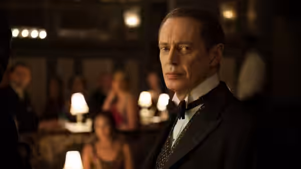 Nucky Thompson (Steve Buscemi) in a tuxedo standing in a crowded restaurant