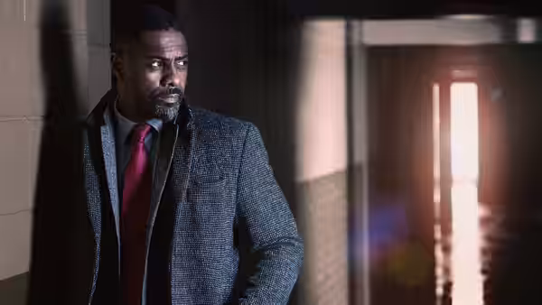 John Luther (Idris Elba) leans against a wall in a dim corridor