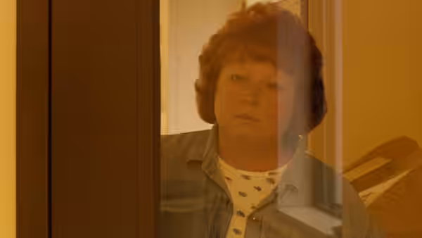 Woman with red curly hair stands in a doorway looking ahead