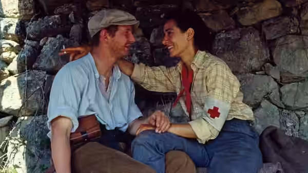 David Carr (Ian Hart) and Blanca (Rosana Pastor) sitting together by a stone wall