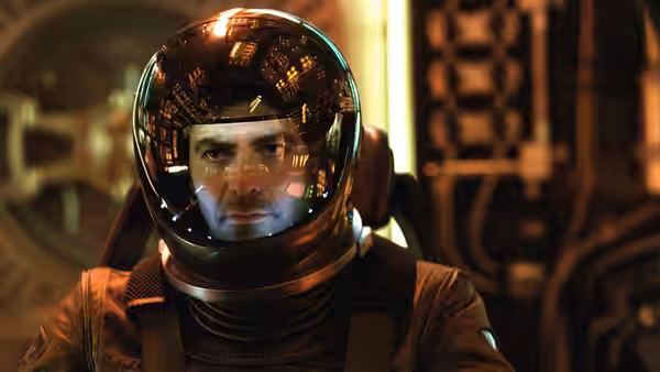 Chris Kelvin (George Clooney) wearing a reflective spacesuit helmet aboard a spacecraft