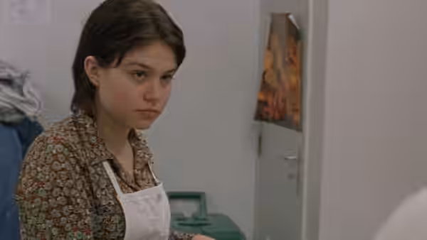 Rosetta (Émilie Dequenne) stands in an apron inside a workroom