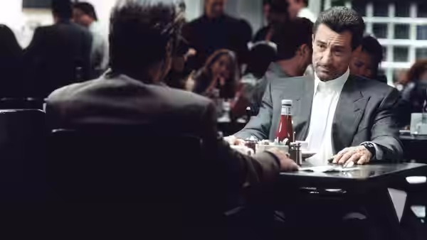 Lt. Vincent Hanna (Al Pacino) seated at a restaurant table with another man
