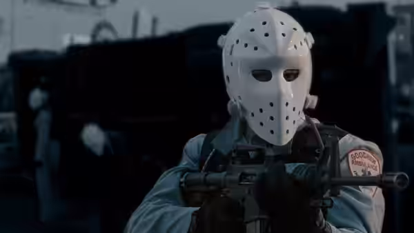 A masked gunman in a paramedic uniform holding a rifle