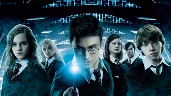 Harry Potter (Daniel Radcliffe) holding a glowing wand with friends in a corridor