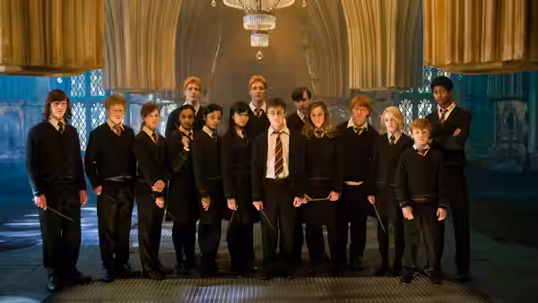 Harry Potter (Daniel Radcliffe) standing with fellow students in a great hall