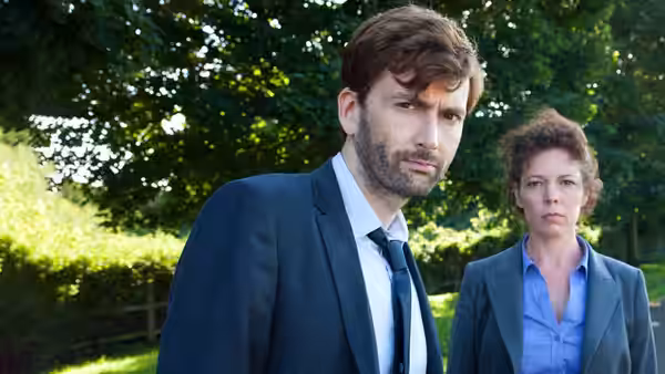 DI Alec Hardy (David Tennant) in the foreground with DS Ellie Miller (Olivia Colman) behind in a garden