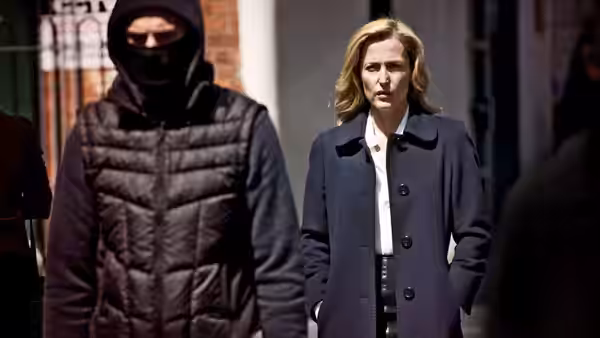 Stella Gibson walking beside a masked man on a city street