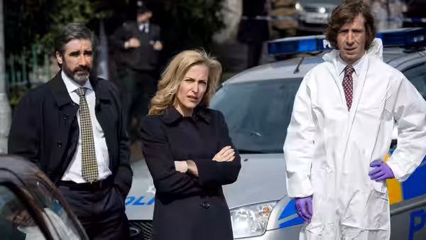 Stella Gibson standing with two men beside a police car at a scene