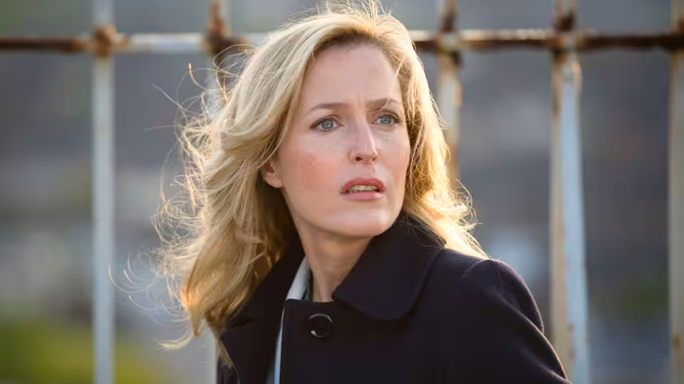 Stella Gibson (Gillian Anderson) standing outdoors with windblown blonde hair
