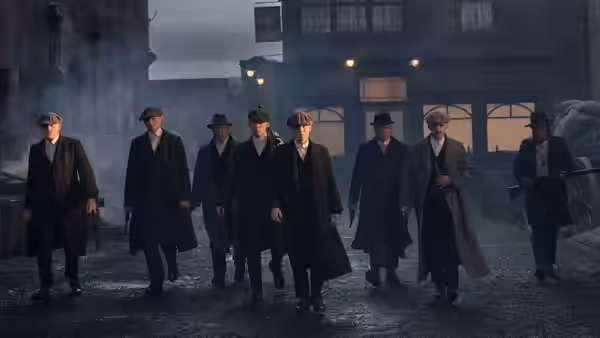Group of men in flat caps and long coats walking down a street