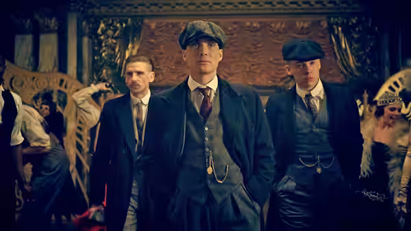 Thomas Shelby standing with two men in a crowded ornate hall