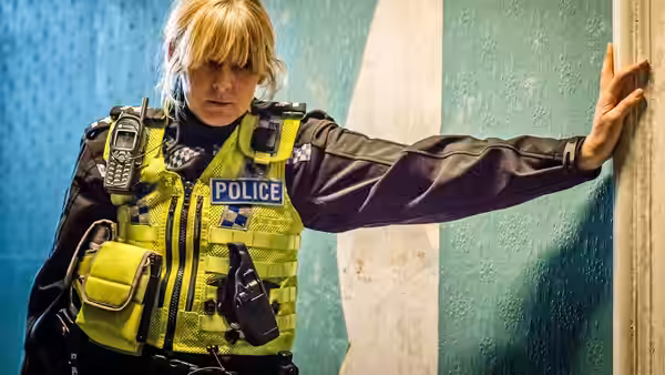 Catherine Cawood (Sarah Lancashire) leans one hand against a painted wall
